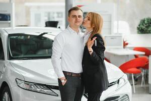 jovem lindo feliz casal comprando uma carro. marido comprando carro para dele esposa dentro uma salão. carro compras conceito foto