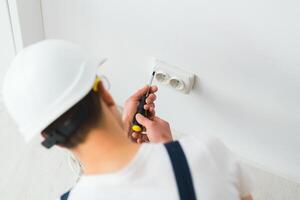 uma jovem eletricista instalando a elétrico tomada dentro uma Novo casa. foto