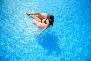 lindo mulher e inflável nadar anel dentro forma do uma rosquinha dentro a piscina foto