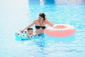 mãe e bebê dentro ao ar livre natação piscina do tropical recorrer. criança Aprendendo para nadar. mãe e criança jogando dentro água. família verão período de férias dentro exótico destino. ativo e saudável esporte para crianças. foto