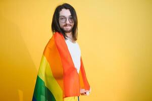 gay homem aguarde arco Iris listrado bandeira isolado em colori fundo estúdio retrato. pessoas estilo de vida moda lgbtq conceito foto