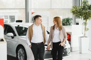 feliz jovem casal escolhe e comprando uma Novo carro para a família dentro a concessionária foto