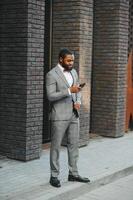 moda retrato do uma bonito jovem africano americano o negócio homem caminhando ao ar livre dentro uma casual pose. foto