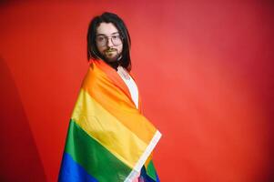 feliz gay homem tendo Diversão segurando arco Iris bandeira símbolo do lgbtq comunidade foto