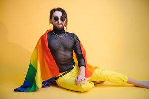 bonito jovem homem com orgulho movimento lgbt arco Iris bandeira em ombro contra branco fundo. homem com uma gay orgulho bandeira. foto