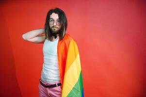 bonito jovem homem com orgulho movimento lgbt arco Iris bandeira em ombro contra branco fundo. homem com uma gay orgulho bandeira. foto