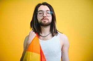 bonito jovem homem com orgulho movimento lgbt arco Iris bandeira em ombro contra branco fundo. homem com uma gay orgulho bandeira. foto