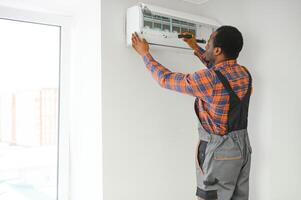 africano americano eletricista reparação ar condicionador dentro de casa foto