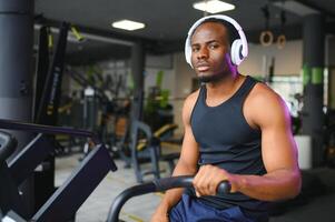 atraente homem às saúde clube, exercício em bicicleta foto