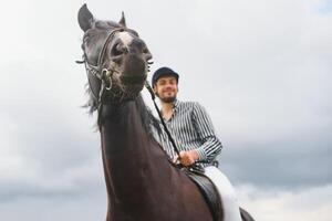 lindo homem equitação uma cavalo em campo às verão foto