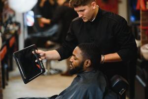 jovem afro-americano homem visitando barbearia foto