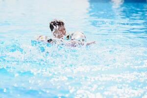 feliz Garoto dentro natação piscina. Garoto é sozinho, natação inflável anel e cercado de água salpicos. molhado adolescente é desfrutando verão final de semana dentro diversão água parque. bandeira com cópia de espaço foto