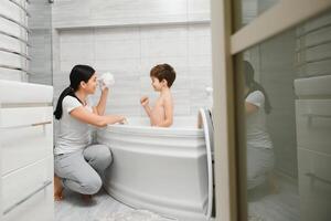 mãe e filho tendo Diversão às banho Tempo juntos foto