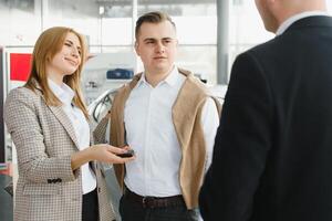 feliz jovem casal escolhe e comprando uma Novo carro para a família dentro a concessionária foto