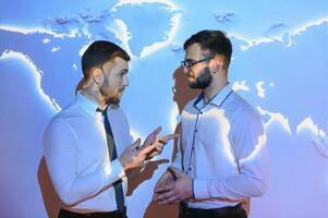 dois atraente jovem europeu empresários em digital mapa azul fundo. comunicação, trabalho em equipe e rede conceito foto