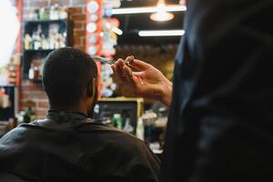 jovem afro-americano homem visitando barbearia foto
