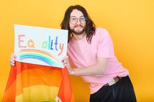 atraente gay caucasiano homem segurando uma protesto placa durante uma lgbt orgulho parada. igualdade. foto