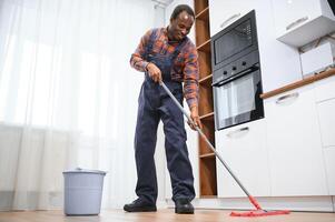 profissional limpador dentro azul uniforme lavando chão e limpando poeira a partir de a mobília dentro a vivo quarto do a apartamento. limpeza serviço conceito foto