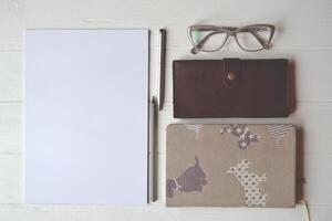 escritório mesa com caderno, caneta, lápis, copos, carteira e branco papel. à moda escritório tem. foto