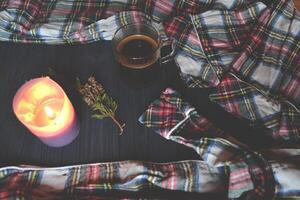 uma copo do café, pijamas e iluminado vela em a de madeira fundo. acolhedor casa estilo. atmosférico cenário. foto