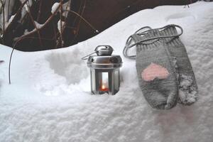 de lã luvas e vela lanterna em a monte de neve. hygge estilo. frio temporada. foto