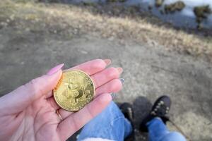 dourado bitcoin dentro fêmea mão. uma moeda do criptomoeda. foto
