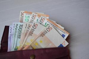 euro dinheiro notas e carteira em a branco de madeira escrivaninha. o negócio dinheiro fundo. foto