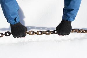 homem segurando grande metal cadeia dentro Nevado clima. foto