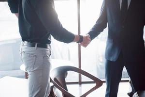 dois confiante homem de negócios apertando as mãos durante uma reunião no escritório, saudação e conceito de parceiro