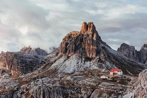 montanhas de paternkofel com nevoeiro e nuvens no topo e edifícios à direita foto