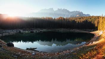 Um novo dia chegou. paisagem de outono com lago claro, floresta de abetos e montanhas majestosas. foto panorâmica