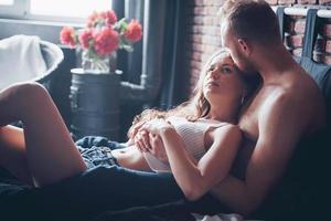 um retrato de um jovem casal feliz que relaxa em uma cama aconchegante foto