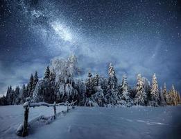 paisagem de inverno. aldeia de montanha nos Cárpatos ucranianos. céu noturno vibrante com estrelas e nebulosa e galáxia. astrofoto do céu profundo