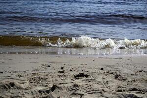 molhado areia e suave ondas em uma de praia. foto