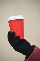 uma mulher mão detém uma papel vermelho descartável copo para café. brincar. Lugar, colocar para logotipo. foto