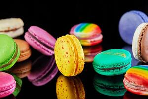 sortido colorida macarons guardada e arranjado em uma Preto superfície com reflexão foto