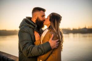 feliz casal se beijando e apreciar gastos Tempo juntos ao ar livre em uma pôr do sol. foto