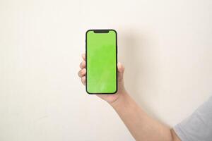 mão é segurando uma telefone com verde tela em uma branco isolado fundo foto