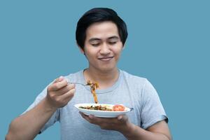 uma homem dentro uma cinzento camisa é segurando uma garfo e uma prato contendo comida, para Projeto e visual edição propósitos. foto