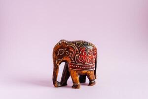 figura do a elefante esculpido a partir de madeira em uma Rosa fundo, feito à mão estatueta, detalhado estude do a estatueta, sagrado indiano elefante, talismã para energia foto