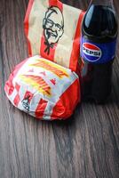 Bangkok, Tailândia - marcha 3, 2024 - kfc frango zinger hamburguer e fresco fritas com Pepsi refrigerante colocada em uma Preto de madeira mesa, Leve embora comida, lixo comida, kfc frito frango, Pepsi Novo logotipo. foto