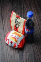 Bangkok, Tailândia - marcha 3, 2024 - kfc frango zinger hamburguer e fresco fritas com Pepsi refrigerante colocada em uma Preto de madeira mesa, Leve embora comida, lixo comida, kfc frito frango, Pepsi Novo logotipo. foto