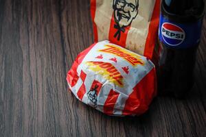 Bangkok, Tailândia - marcha 3, 2024 - kfc frango zinger hamburguer e fresco fritas com Pepsi refrigerante colocada em uma Preto de madeira mesa, Leve embora comida, lixo comida, kfc frito frango, Pepsi Novo logotipo. foto