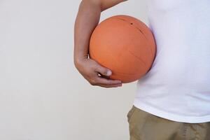 fechar acima homem detém laranja basquetebol. conceito, esporte equipamento. exercício para saúde. saudável estilo de vida.trabalho Fora faz Forte do corpo. foto