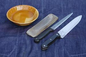 tigela do água, moedor pedra e facas, preparar para afiação. conceito, manutenção Ferramentas para culinária, faço faca afiado ,não maçante para grandes viver usando. original estilo para aguçar faca. foto