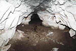 calcário caverna, argila com água em a chão do a caverna passagem, carste buraco, Sombrio corredor subterrâneo, espeleologia. foto