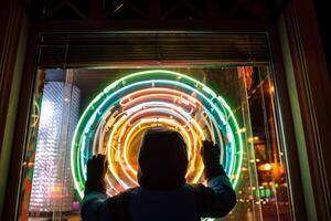 silhueta do uma pessoas mão para a lados contra uma fundo do colori círculos. silhueta às noite dentro a cidade. foto