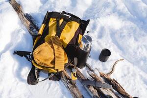 acampamento equipamento Visão a partir de acima. equipamento para uma inverno caminhar para 1 dia. amarelo cor do a mochila, chapéu, garrafa térmica com caneca. foto