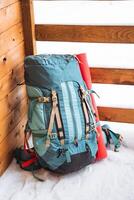 uma brilhante caminhada mochila mentiras em a chão fora. uma escalada corda é amarrado para uma mochila. dentro a lado bolso do a garrafa térmica. caminhada dentro inverno. pedras e florestas foto