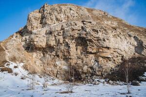 Rocha Entrada para a caverna Karlamanskaya Rússia sulista urais bascortostão, inverno paisagem, Primavera dentro a floresta a Sol aquece, caloroso clima, azul céu foto